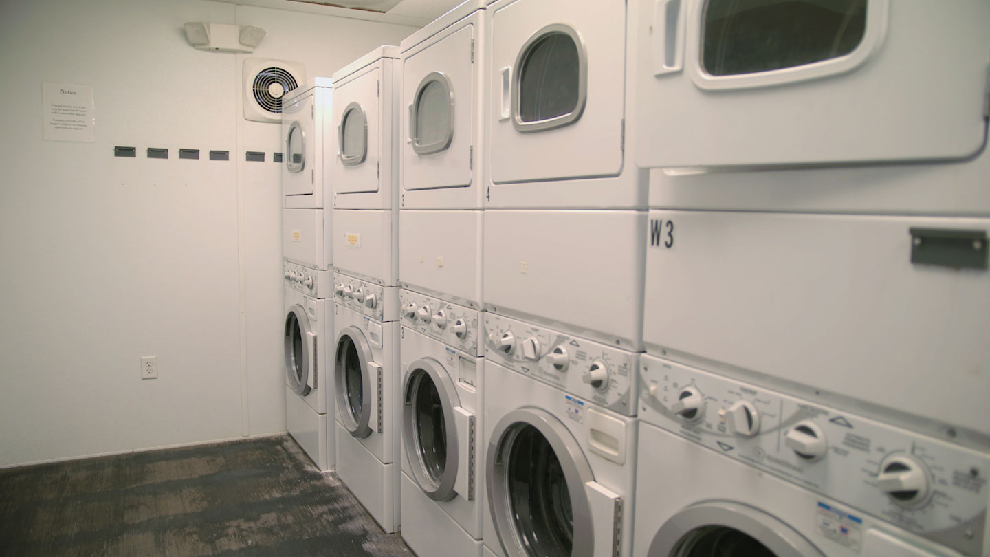 A photo of an interior of a laundry room, depicting rows of washer and dryer machines.