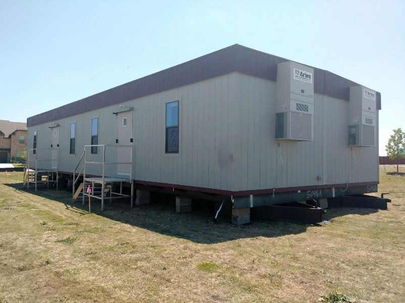 This image depicts one of Aries modular buildings serving as temporary office space on a grassy field near a government building