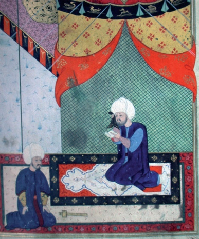 A colorful painting portraying two kneeling men, with facial hear and turbans, facing each other in an offset position, one of them on an artistic decorated rug. They are inside of a tent with red, blue, green, and yellow interior.