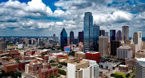 A panoramic shot of the city of Austin, Texas downtown featuring a skyline filled with skyscrapers under a blue sky filled with puffy white clouds.
