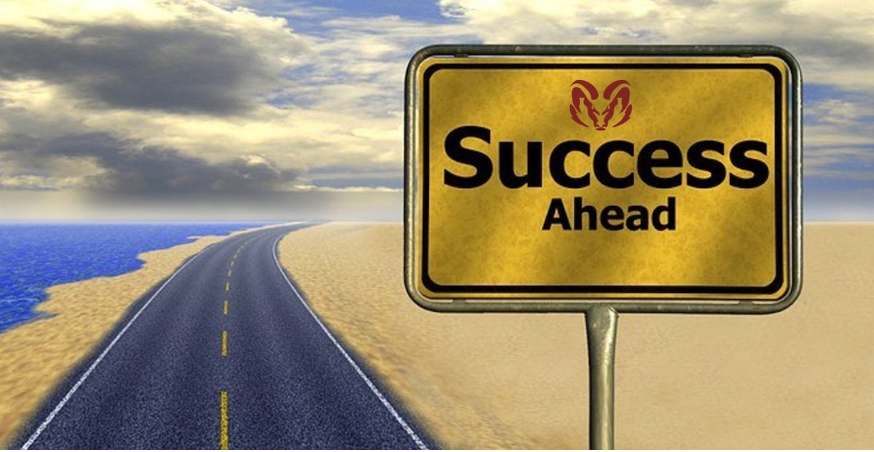 A computer rendered image of a two-lane road bordered by sand on one side and a beach shore on the other disappearing into the distance, and at the front of the picture, a yellow and black road sign reads “success ahead”.