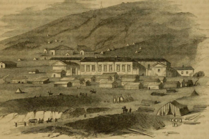 An aged sketch of a big house with hills behind it. At the lower right of the drawing is a tent with a few piles of cut wood surrounding it. A wagon is making its way up a little hill in the lower left corner. Many tents and small buildings rest in front and behind the main house.