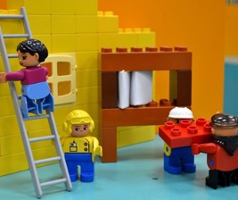 : A depiction showing a construction site and four men working using Lego bricks.
