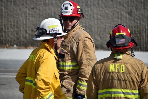 A group of firefighters in their gear discussing an emergency plan of action.