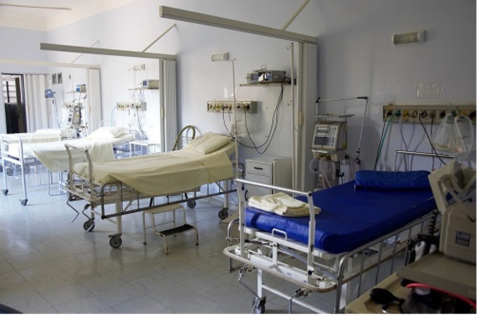 Photograph of a hospital room with four empty beds and equipment ready for an emergency situation..