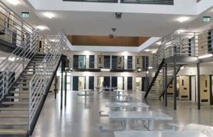 The inside of the NSW Corrections prison is shown just outside the cells and a couple of staircases in a common area with tables.