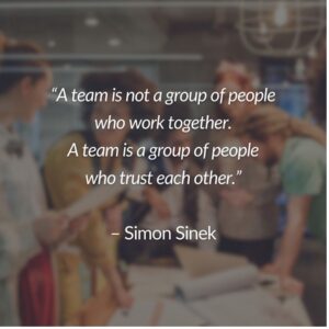 A blurred image of a group of people standing around a table. On the center of the image is the words, “A team is not a group of people who work together. A team is a group of people who trust each other.” – Simon Sinek”
