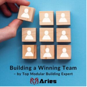 A hand holding one of the many blocks with icons of people on it that is sitting on top of a blue surface. On the bottom is the blog title which is, “Building a Winning Team-by top modular building expert” and under that is the logo of Aries.