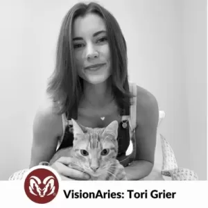 A black and white photo of VisionAries Tori Grier smiling with her cat.