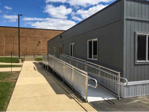 A portable classroom with a ramp and railings on a sunny day, showcasing the flexibility and cost efficiency of educational space solutions.