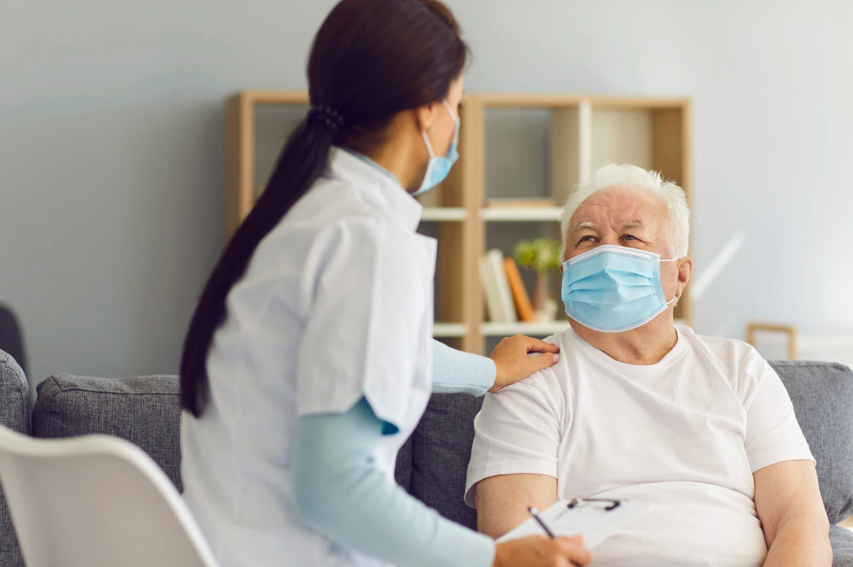 A nurse consulting with a smiling patient and both are wearing facial masks.