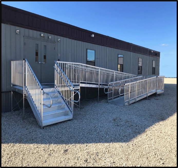 Portable classroom provided by Aries Buildings with a metal ramp on a sunny day.