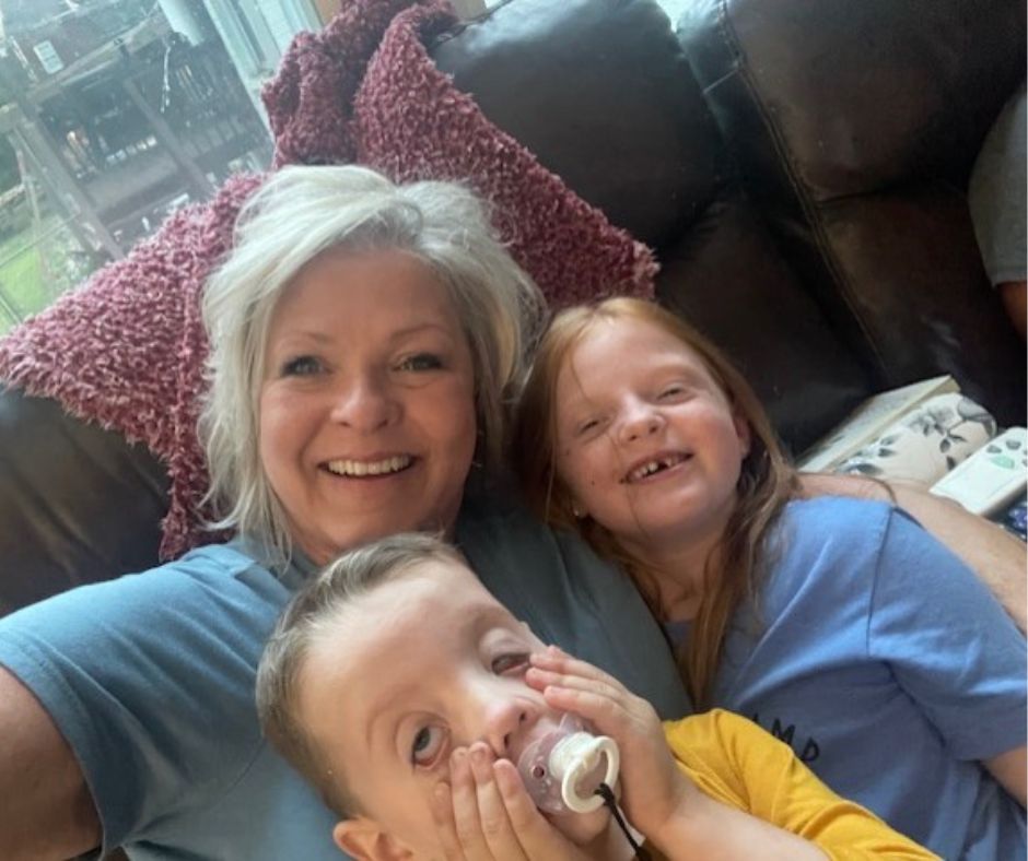 A selfie of Traci with two smiling children on the couch.