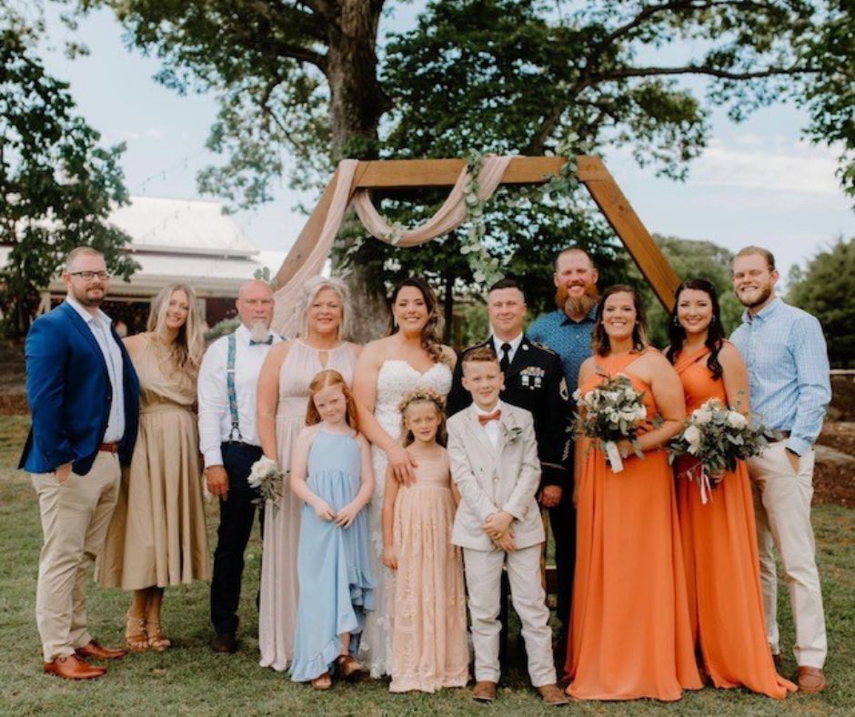 Photo of Traci's extended family smiling at a wedding video. They are all dressed in formal attire and posed for the photo.