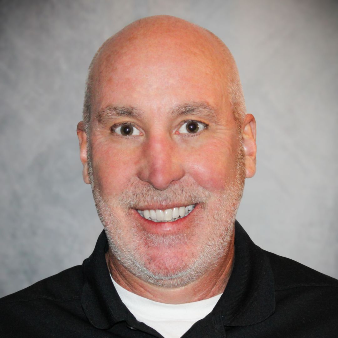 Headshot of Joe Hartwell Aries' Territory Sales Manager in Tucson, AZ. He is smiling, wearing a black collared shirt, has brown eyes, and facial hair.