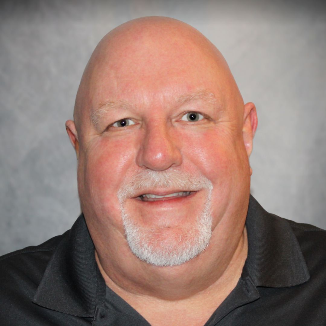 Headshot of Steve Yantzer, Territory Sales Manager for Aries Buildings in Bellevue, WA. He is bald with white facial hair, wearing a blacl collared shirt.