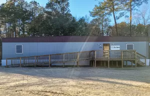 Photo of Aries Buildings' office in Clayton, NC. It is a mobile office trailer with an Aries sign and a ramp leading up the the front entrance.