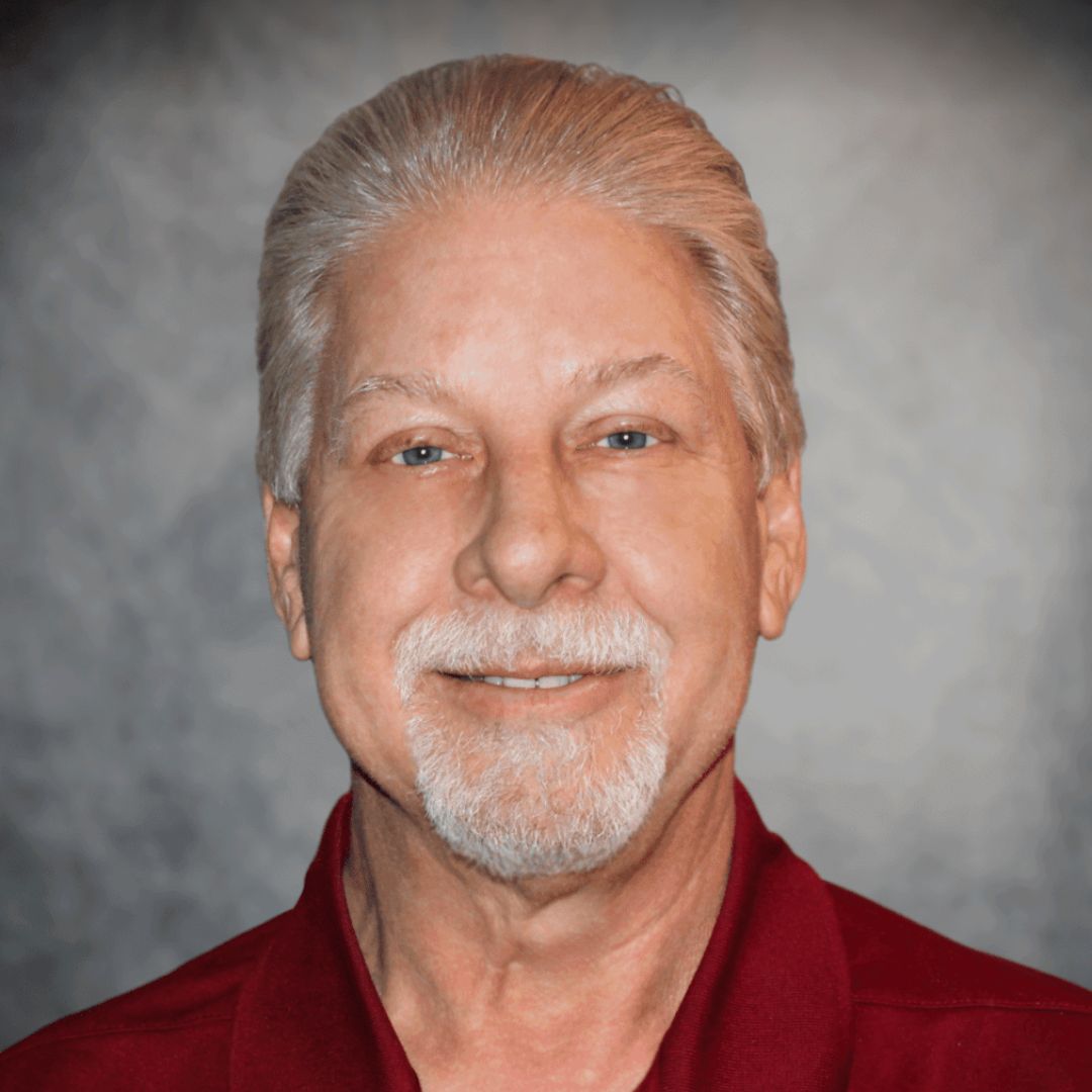 Headshot of Chris Kessler, Sales Associate in Cleburne, TX for Aries Buildings. He is wearing a maroon collared short and has white hair.