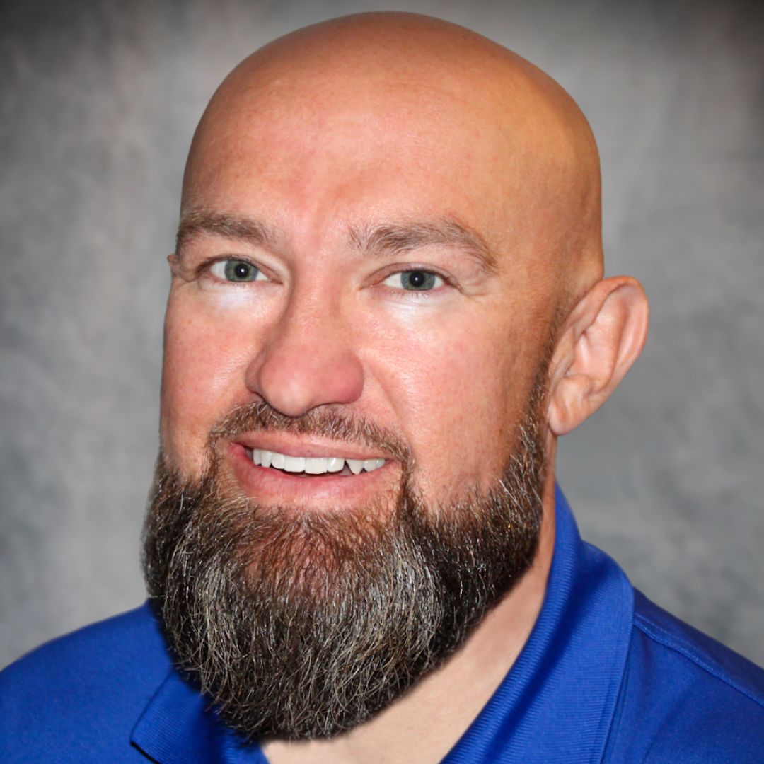 Headshot of Jason Ellis, Territory Sales Manager for Aries Buildings in Aurora, IL. He is bald, has a thick beard, and is wearing a blue collared shirt.