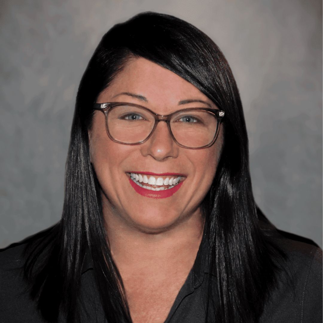 Headshot of Stacy Vetter, Sales Associate for Aries Buildings in Cleburne, Texas. She has dark black hair, glasses, and is wearing a black collared shirt.