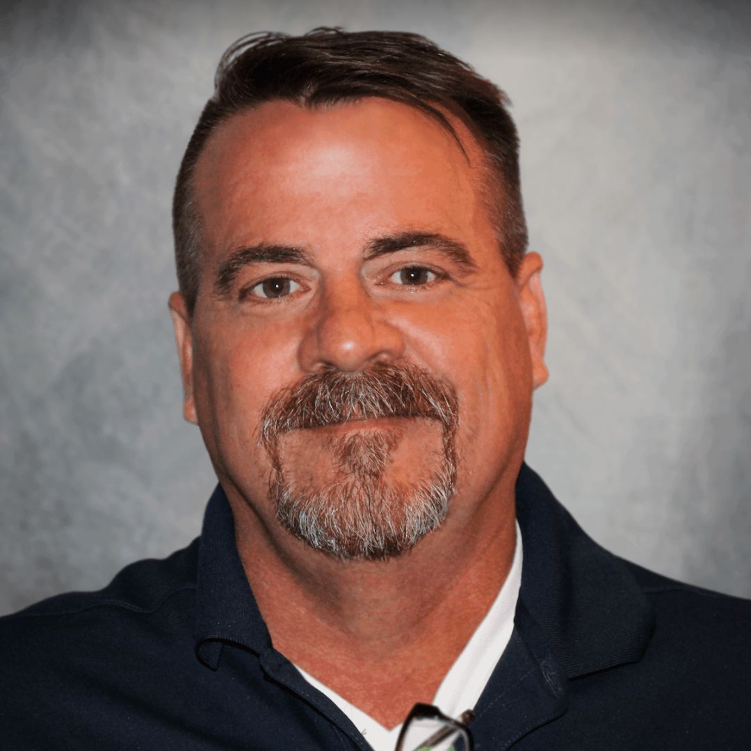 Headshot of Tom Pieper, Territory Sales Manager for Aries Buildings in Holt, MO. He has short brown hair, facial hair, and is wearing a black collared shirt.