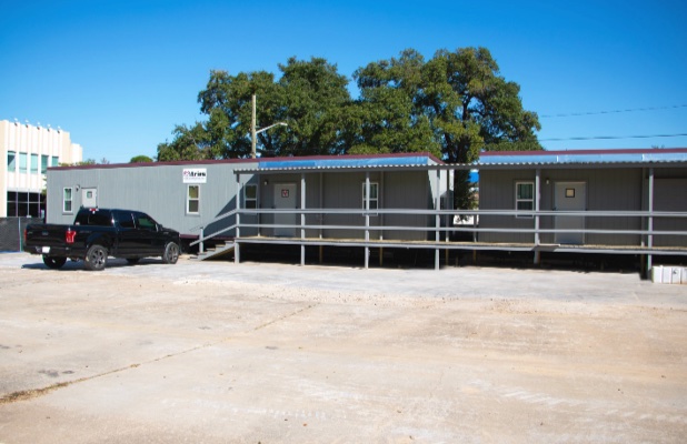 Two mobile offices with metal ramps and black truck parked in front, on a sunny day.