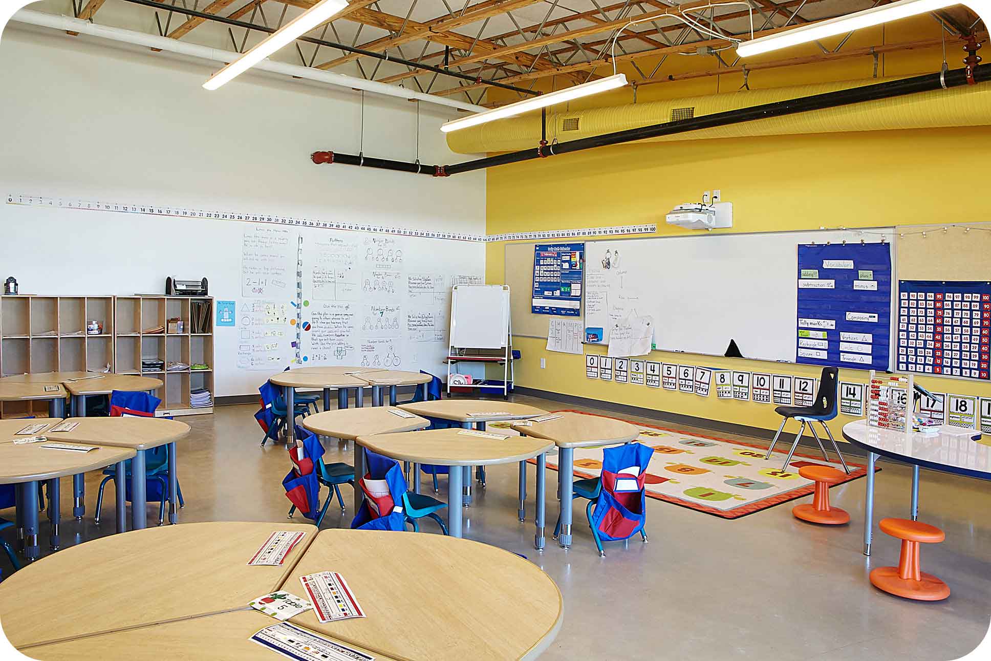 A traditional Aries modular classroom featuring rows of desks, a ceiling-mounted projector, and wall posters. This setup illustrates the evolution of technology in Aries modular classrooms.