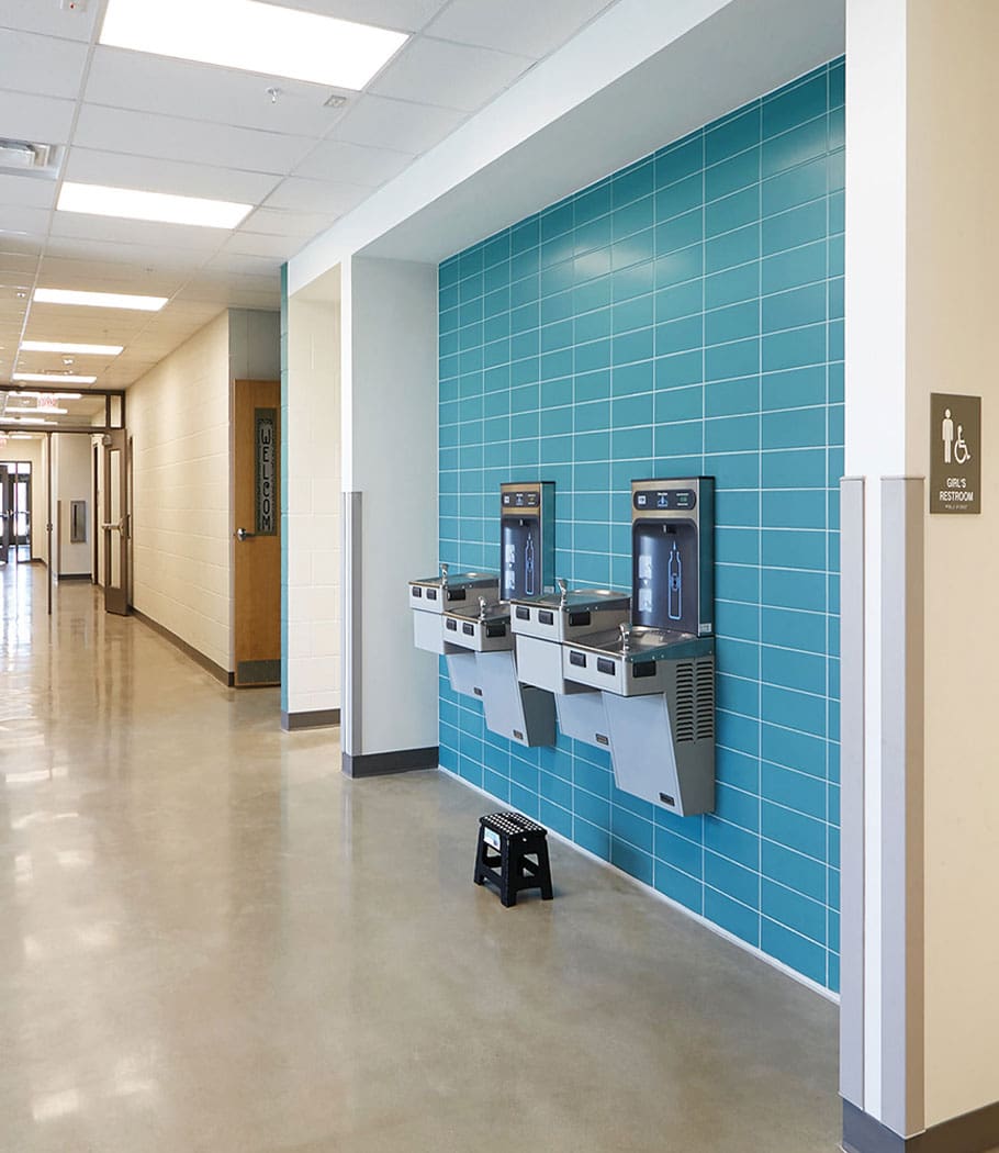 Spacious modular school hallway featuring ADA-compliant water fountains and accessible restroom signage.