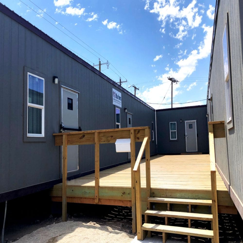 Mobile offices for construction is positioned on-site, featuring modular units with stair access and external air conditioning systems.