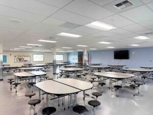 Interior of a modular school building featuring a bright cafeteria space with tables and modern finishes.
