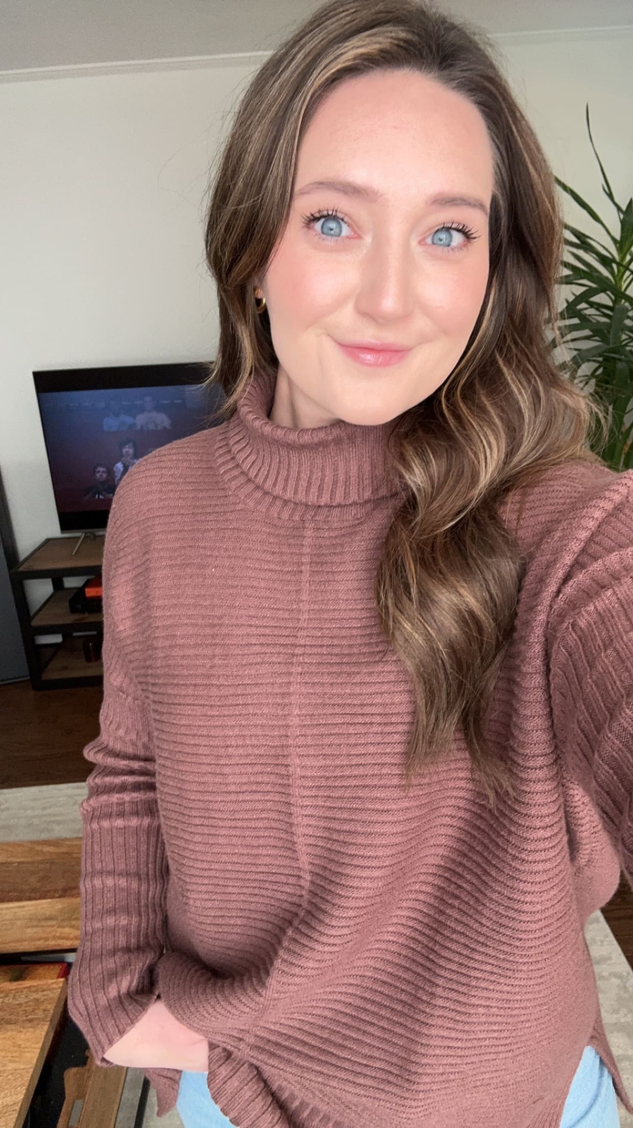 A selfie of VisionAries Spotlight and Sales Associate, Bailey Beck, soft smiling in a pink turtleneck sweater.